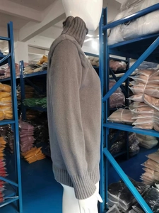 Detail of grey cable knit turtleneck sweater showing thick texture and ribbed cuffs
