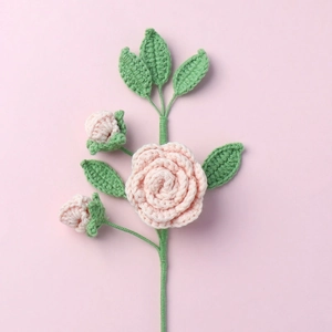 Dettaglio di un ramo di camelia rosa fatto a mano all'uncinetto con trama in filato e foglie