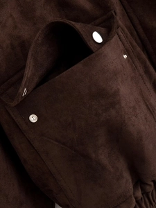 Detail of brown faux suede jacket featuring a flap pocket with a silver metal snap button