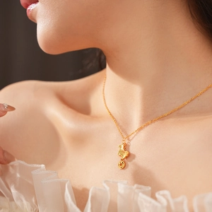 Close-up of gold plated necklace with animal pendant and small copper coin charm