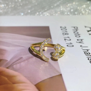Detail shot of golden open ring with crescent and spherical shapes set with gems