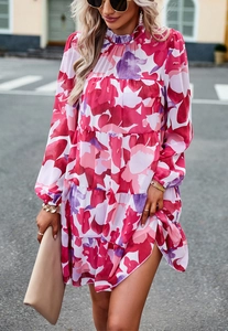 Détail d'une robe courte fleurie rose avec jupe à volants et manches longues