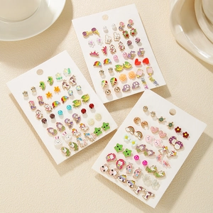 Detail view of colorful cartoon enamel stud earrings featuring unicorns and rainbows