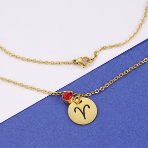 Detail of Aries constellation pendant with red birthstone on gold stainless steel chain