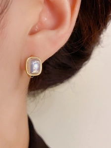 Close-up of small square pearl ear cuff in gold plating worn on a female ear
