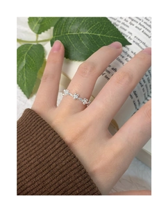 Detailed view of silver flower band ring on hand against a decorative nature background