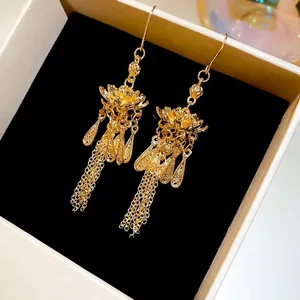 Goldene Lotus-Quastenohrringe mit hohlem Blumendesign in einer schwarzen Schmuckschatulle