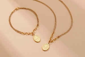 Detailed view of gold multi-layer chain set with oval coin pendant on beige background