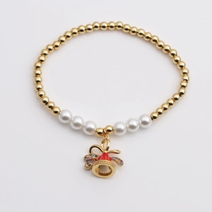 Detail of beaded bracelet with gold metal spheres, pearls and a red enamel bell charm