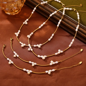 Elegant gold titanium steel jewelry set featuring white freshwater pearls on silk fabric