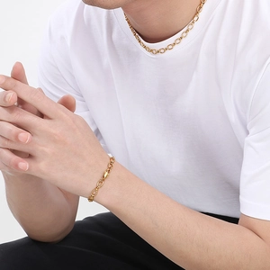 Gros plan d'un bracelet chaîne en O en acier inoxydable doré porté au poignet