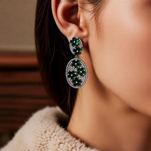 Macro shot of vintage silver-plated earrings with green zircon flower drop on a model
