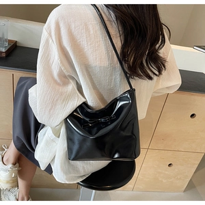 Detail of black patent leather shoulder bag with elegant ribbon bow decoration