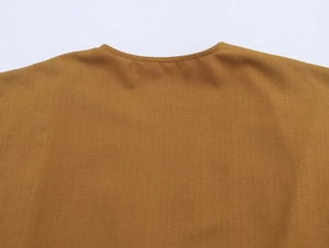 Detail of camel blouse back neckline showing fine crepe fabric texture and clean stitching