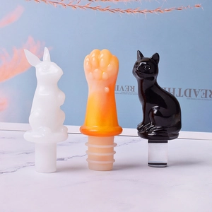 DIY resin wine bottle stoppers in bunny, cat paw, and cat designs on marble surface