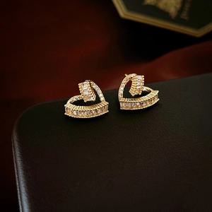 Elegant gold heart earrings with cubic zirconia stones displayed on a black jewelry box