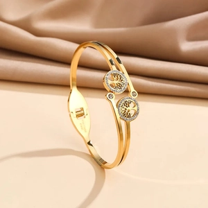 Gold plated stainless steel open bangle featuring cut-out tree of life charms with crystals