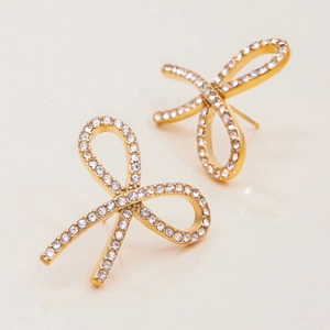 Elegant gold bow earrings with sparkling white rhinestones in a minimalist studio shot