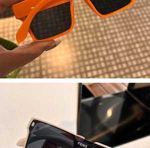 Close-up of square thick-frame sunglasses in bright orange and black with side logo detail