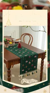 Close-up of dark green Christmas table runner with festive patterns and tassel trim