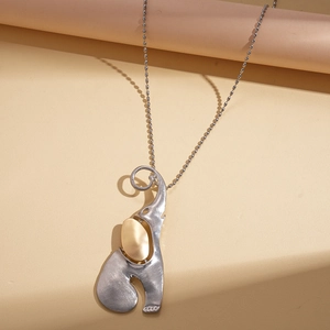 Detail shot of silver and gold elephant pendant necklace with fine bead chain texture