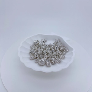 Macro shot of silver zircon pavé spacer beads on a white shell tray for jewelry making
