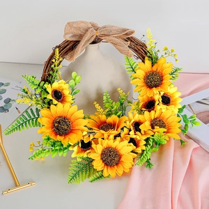 Artificial sunflower wreath on vine base with burlap bow and green fern leaves decor