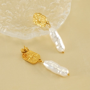 Elegant gold starburst stainless steel earrings with white baroque bar pearls on beige fabric