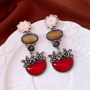 Vintage silver flower drop earrings with amber and red stones on a white relief plate