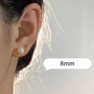 Close-up of a minimalist 8mm white pearl stud earring worn on ear with soft lighting