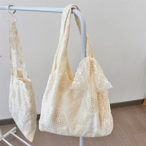 Detail of cream floral eyelet lace tote bags featuring delicate embroidery and ribbon bow