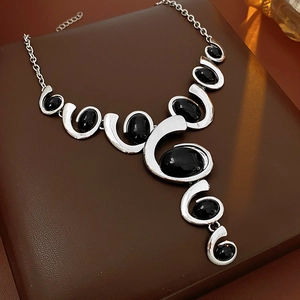 Macro shot of silver geometric necklace featuring a black oval gemstone on leather base