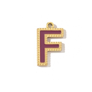 Detail of vintage gold F-letter pendant with deep purple enamel and textured edges