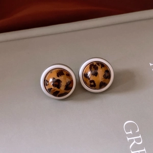 Gros plan de boucles d'oreilles rondes à imprimé léopard avec bord blanc brillant