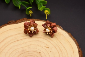 Macro shot of brown floral earrings with pearls on a natural wood textured background