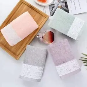 Close-up of coral fleece towels featuring wide white floral lace trim in pastel colors