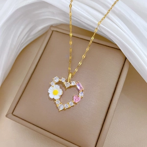 Detailansicht goldener Herzanhänger mit Zirkonia und Gänseblümchen auf einer Schmuckbox