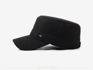 Detail view of black winter flat cap featuring twill fabric texture and diamond metal badge