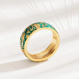 Close-up of golden ring with green enamel, leaf patterns, and sparkling crystal details