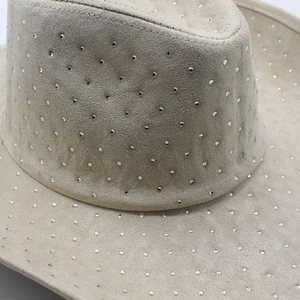 Macro detail of beige suede cowboy hat with sparkling rhinestone studs along the seam