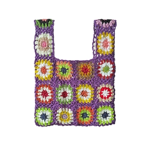 Detail of crochet tote bag with colorful granny square floral patterns and twin handles