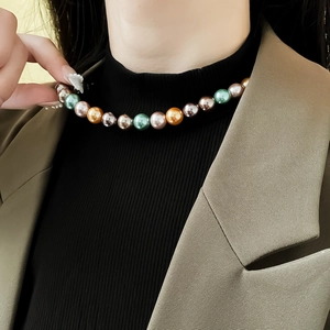 Gros plan d'un bracelet en perles multicolores aux tons champagne, vert et violet