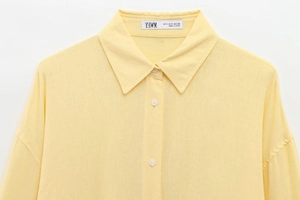 Close-up of pale yellow shirt collar and label showing stitching details and texture