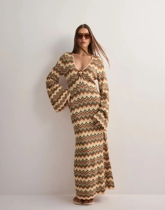 Dettaglio dell'abito in maglia con scollo a V, maniche a campana e motivi boho