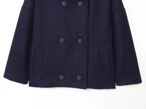 Detail view of the navy blue double-breasted coat showing front buttons and pocket