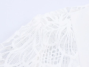 Detailed macro view of white lace floral embroidery on an elegant blouse shoulder