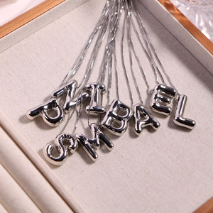 Elegant silver balloon style alphabet pendant necklaces on a cream velvet jewelry tray