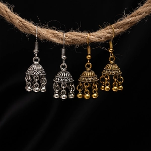 Detail of vintage bohemian bell earrings with floral carving on coarse hemp rope