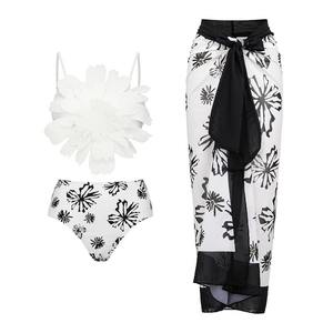 Detailed view of 3D white flower on swimwear and matching abstract print sarong wrap