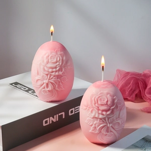 Detalle de velas rosas en forma de huevo con relieves de rosas sobre una caja